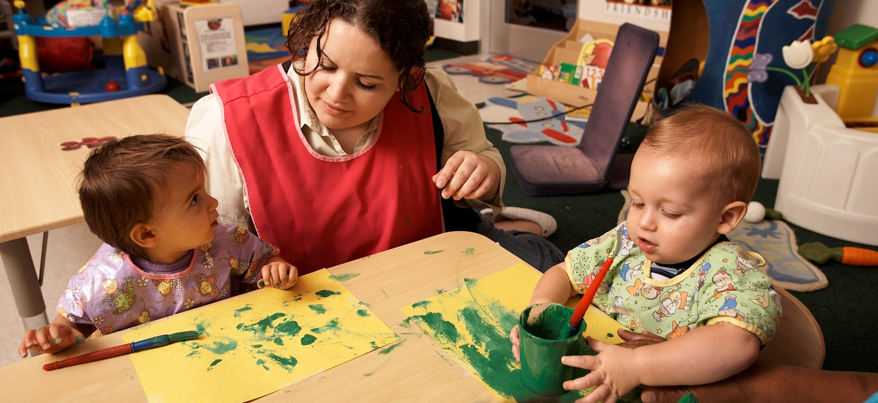 toddlers finger painting with teachers